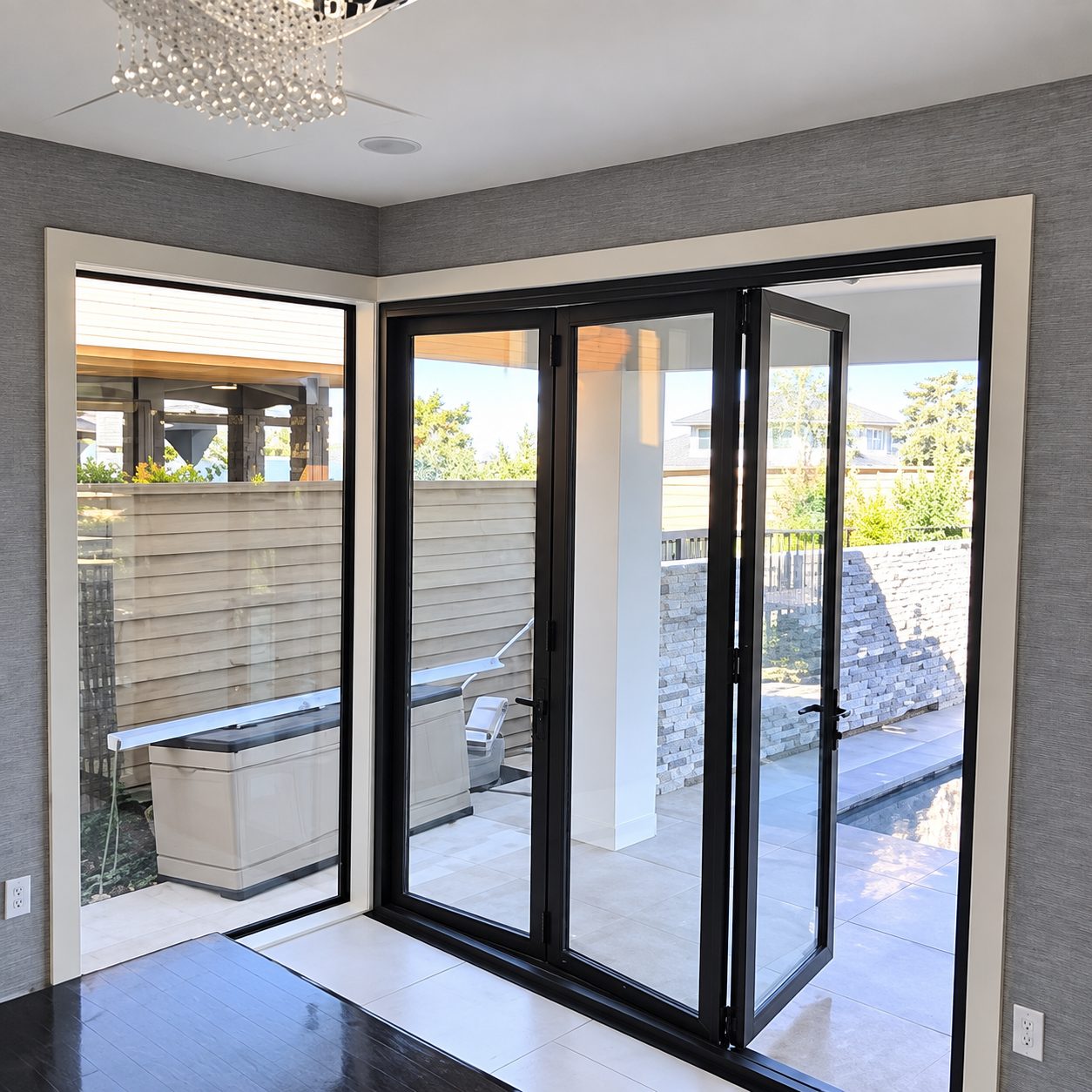 Black-framed bi-fold glass doors in a bright corner room