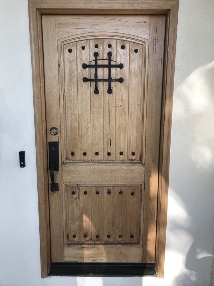 Rustic knotty wood entry door with iron speakeasy grille and clavos
