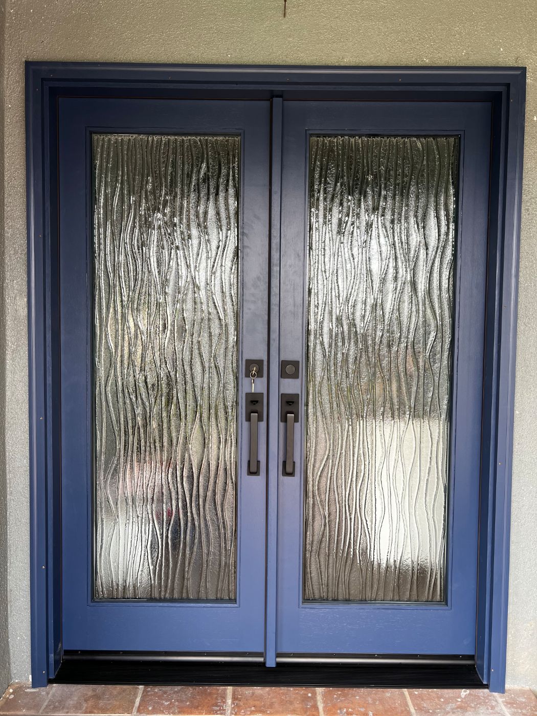 Navy blue double entry doors with full-length textured wave glass
