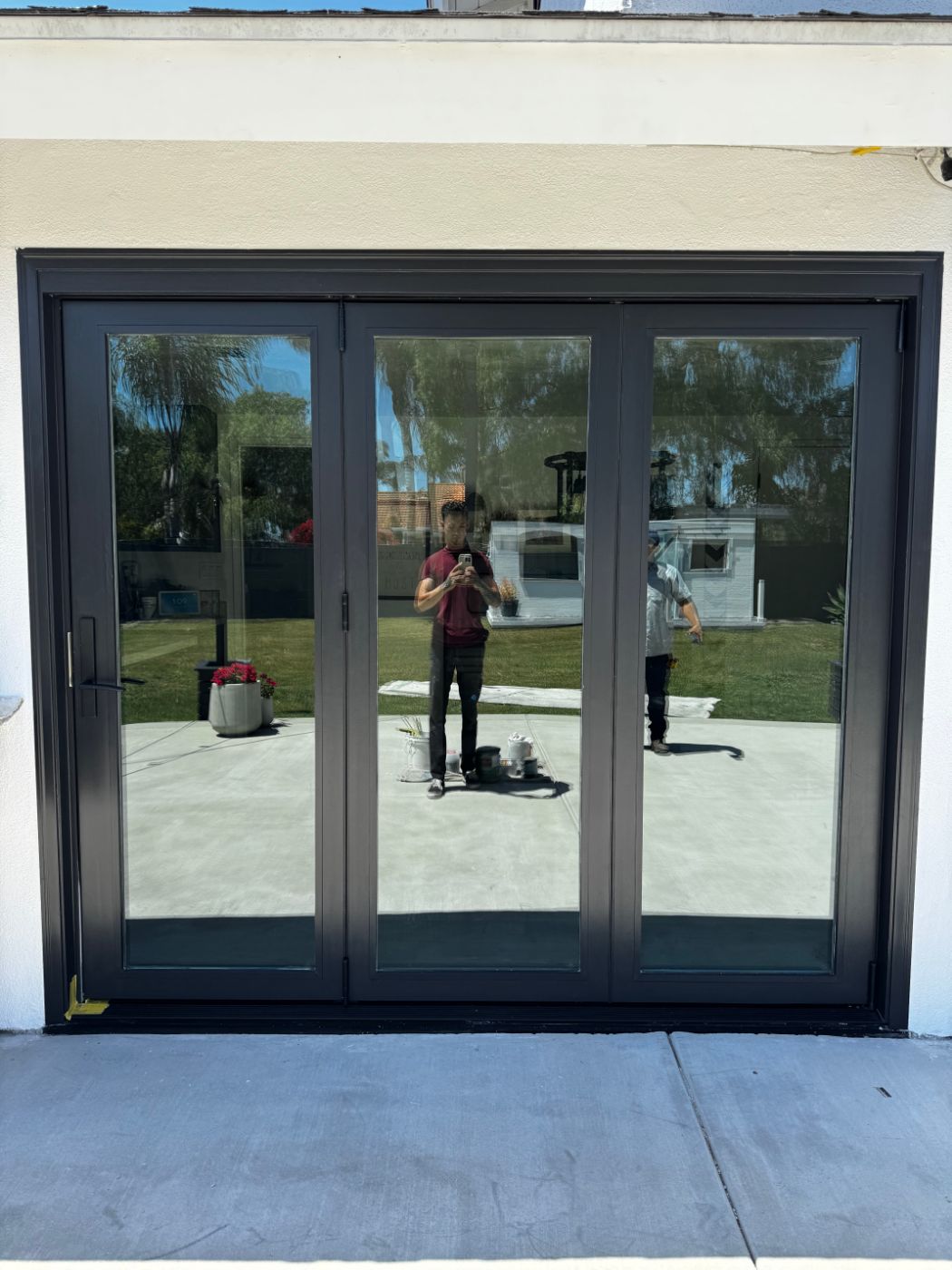 Three-panel black folding glass door opening to a backyard patio