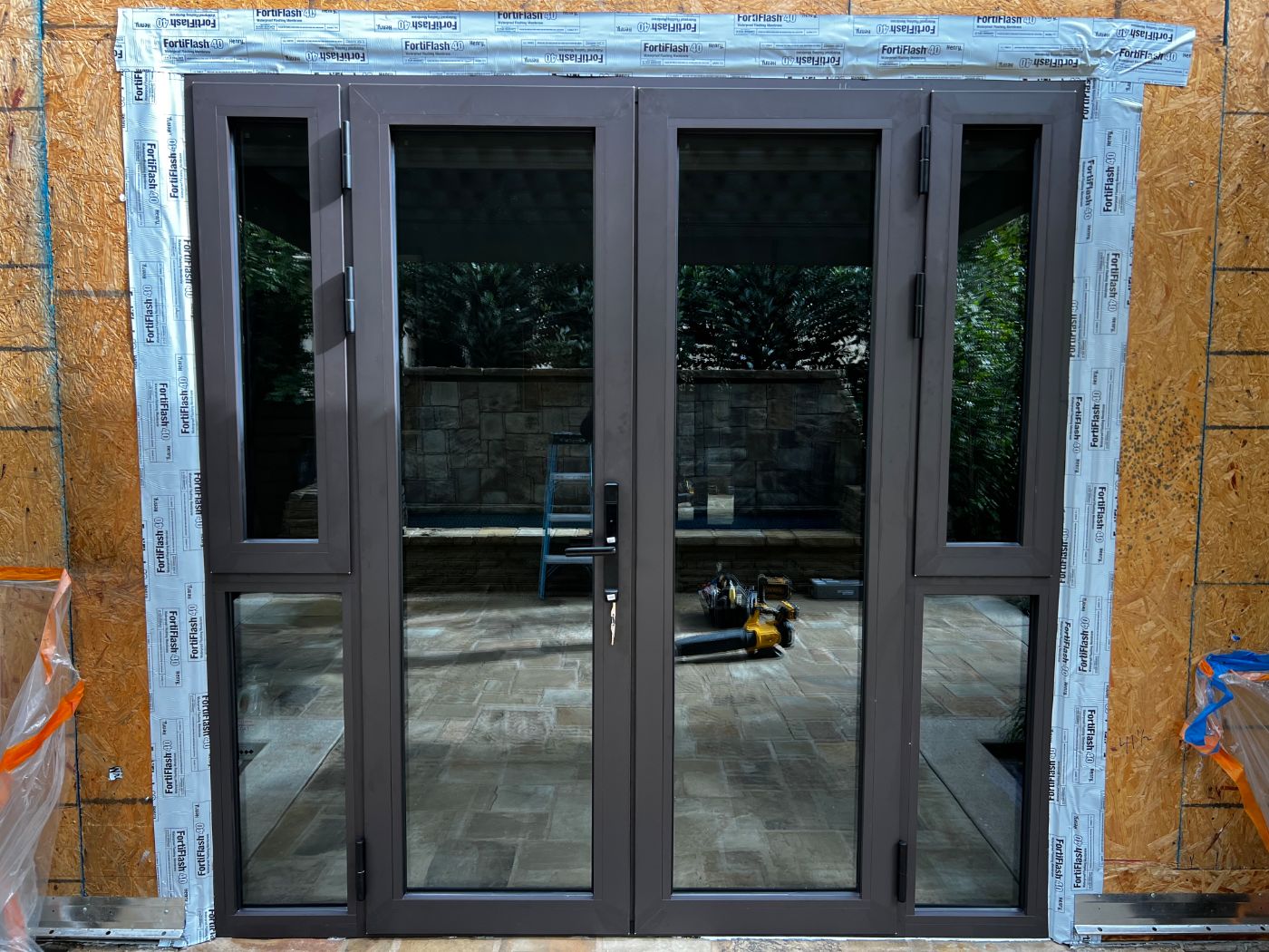 Dark bronze French doors with sidelites, installed in a new exterior opening