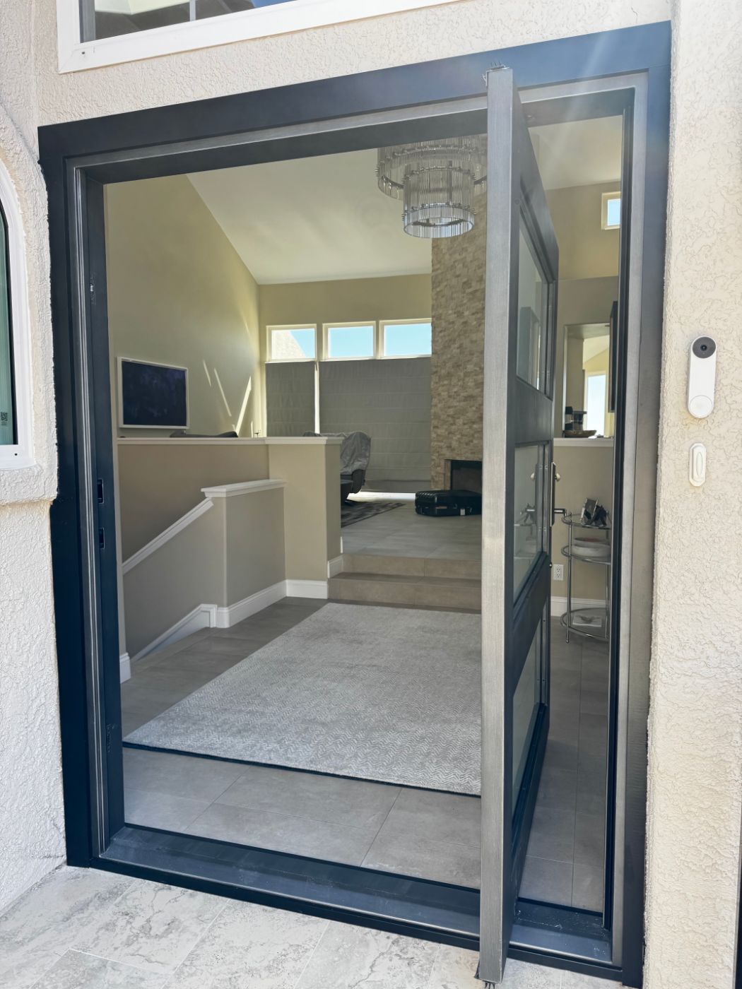 Steel-framed glass pivot door open to a bright living room