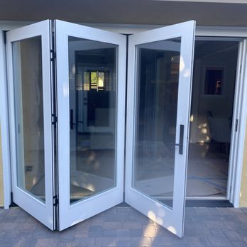White bi-fold glass doors folded open onto a brick patio