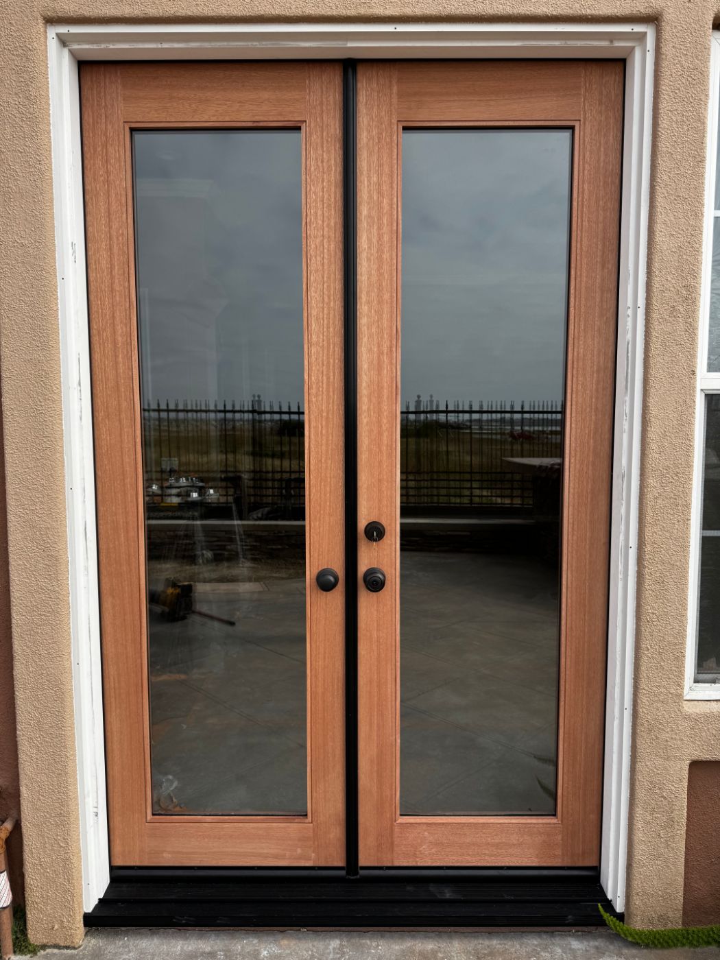 Mahogany full-glass French doors installed in a stucco exterior